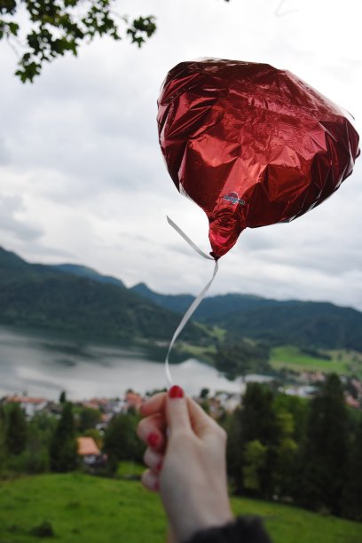 手持红气球与风景的特写图片下载