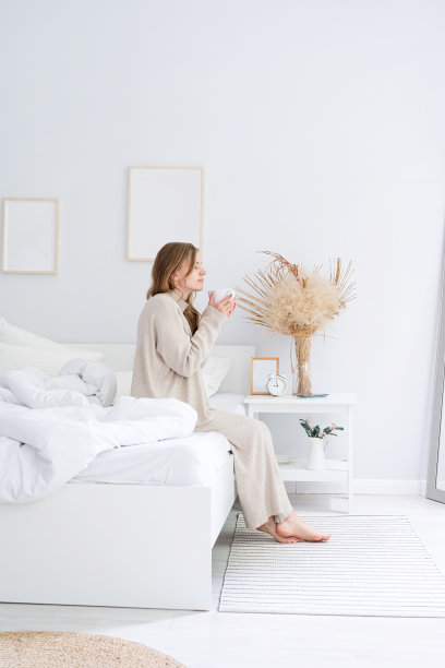 女人坐在家里的床上喝咖啡图片下载