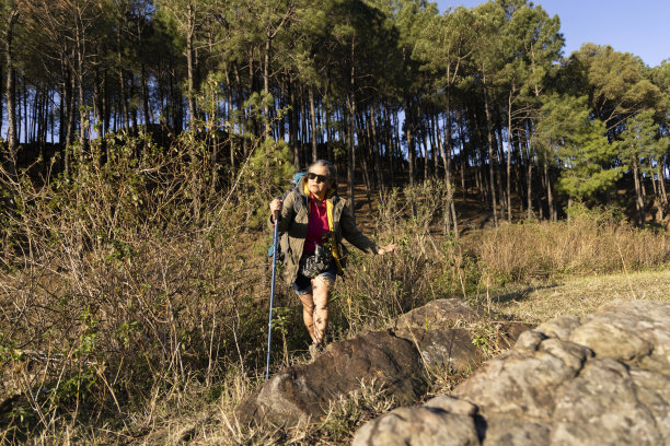 开朗活泼的白发老妇人背着背包在大自然中远足图片下载