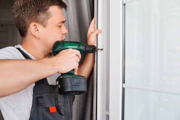 修理工修理或调整阳台上的窗框或玻璃门。图片下载