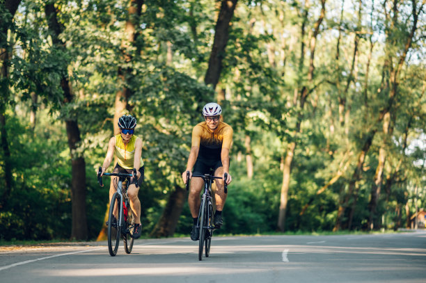 一对夫妇在城外骑自行车，戴着头盔和太阳镜图片下载