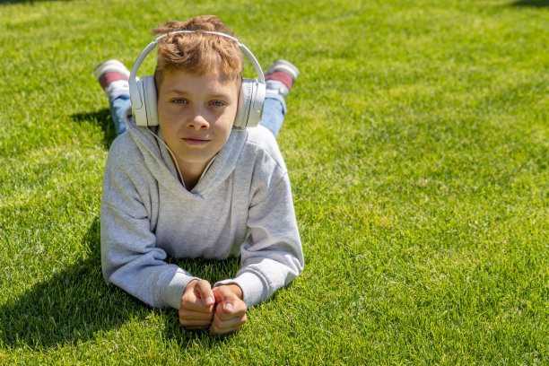 一个男孩在草地上放松，听着音乐图片下载