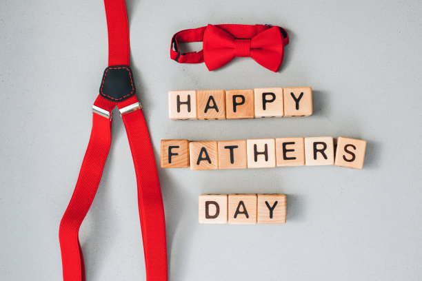 父亲节概念快乐。背景，祝贺卡。灰色的混凝土背景上摆放着黑色字母的木制立方体，红色的男士配饰、领结和背带裤图片下载