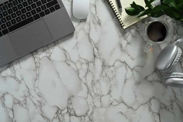 笔记本电脑，记事本，耳机，记事本和咖啡杯放在大理石桌上。带复制空间的俯视图。图片下载
