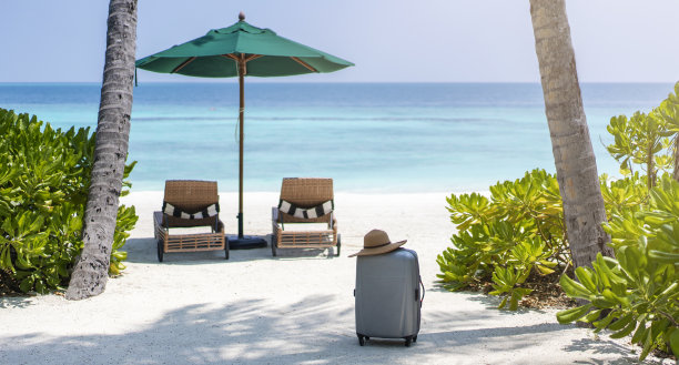 一个行李箱和一顶草帽映衬着马尔代夫的风景。旅游和热带度假的概念图片下载