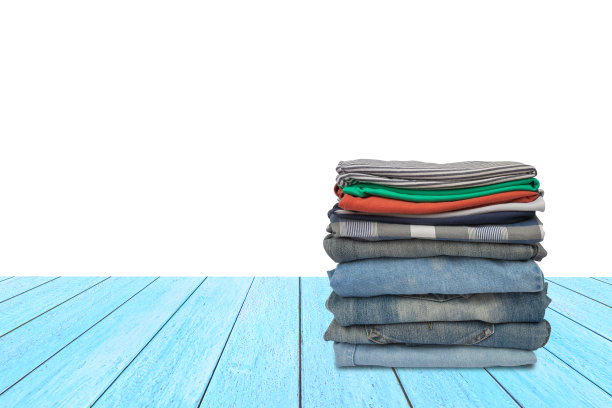 一堆洗干净的整齐的衣服放在白色背景的蓝色木桌上。图片下载