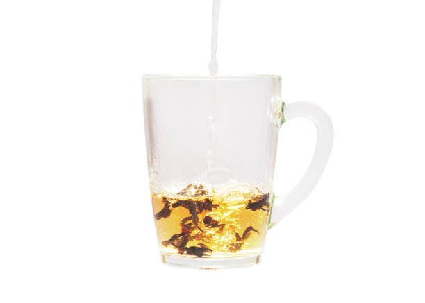 向装有茶叶的透明杯子中加水。图片下载