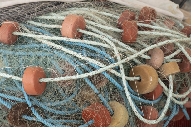 从一艘堆放在渔港的船上，仔细观察工业捕鱼中使用的渔网、浮标和其他物品。图片下载