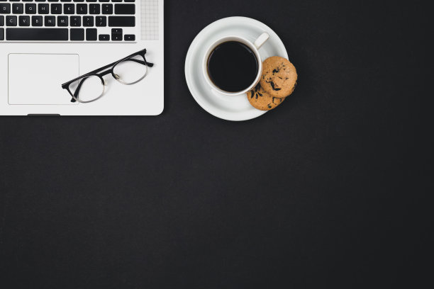笔记本电脑，眼镜，一杯咖啡和黑底饼干。图片下载