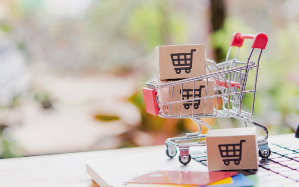 网上购物。信用卡和印有购物车标志的纸板箱放在手推车上的笔记本电脑键盘上。网上购物服务。提供送货上门服务图片下载