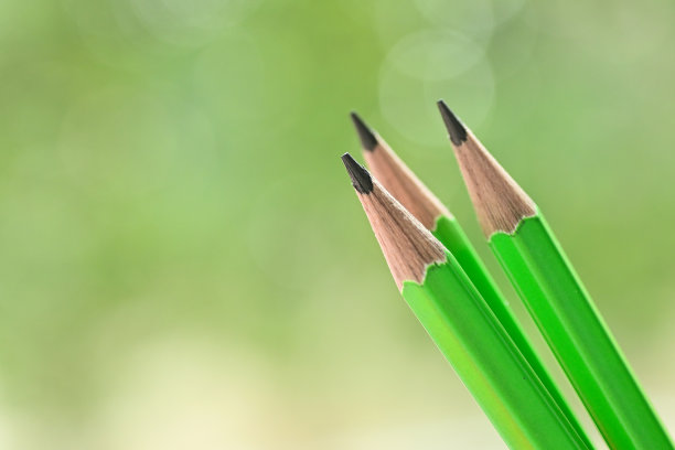 三尖的绿色木制铅笔在模糊的自然背景与散景图片下载