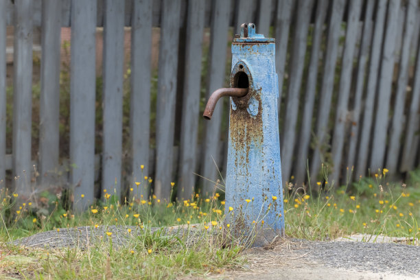 村子里有一根旧水柱，上面有蓝色的裂缝。饮用水供应柱的特写。图片下载