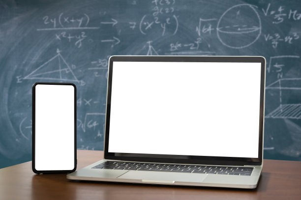 笔记本电脑，智能手机，空白屏幕放在木桌上作为前景。黑板上有数学内容，书写有多种颜色。图片下载