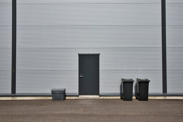 灰色工业仓库墙，门和垃圾桶图片下载