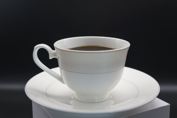 黑咖啡倒进黑色背景的瓷咖啡盒里图片下载