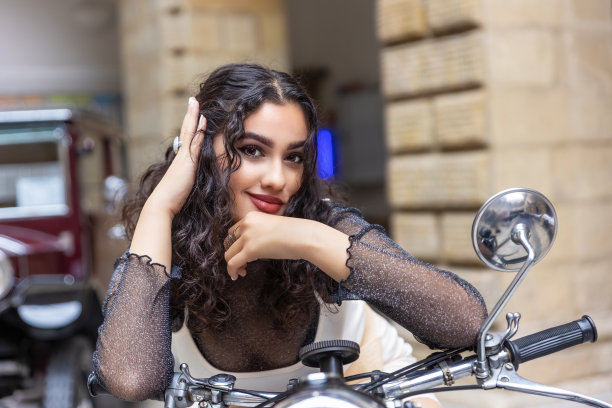 晒黑的女孩坐在一辆老式摩托车上。图片下载