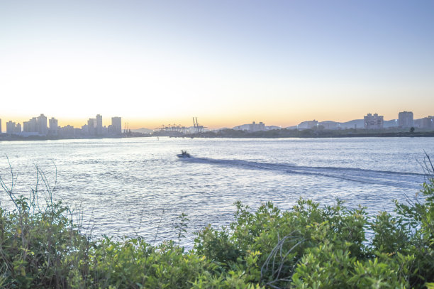 船在海上航行，夕阳和城市在背景中，城市的名字是Itajai-sc图片下载