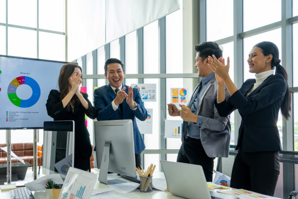 在现代化的办公室里，一群同事一起欢呼和庆祝成功图片下载