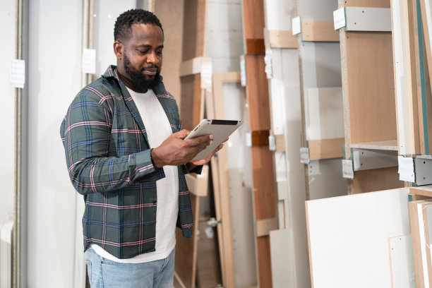 非裔美国木匠在木材厂用木板使用平板电脑图片下载