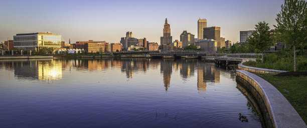 普罗维登斯市中心的天际线和日出时的建筑物，罗德岛州首府河上平静的水面倒影图片下载