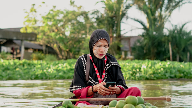 南加里曼丹的Lok Baintan水上市场上，水上市场的小贩在玩手机图片下载