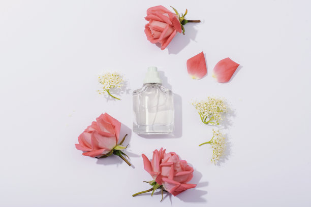 玻璃香水瓶和珊瑚粉色玫瑰花在白色的背景与刺眼的阴影。俯视图，平躺，模型图片下载