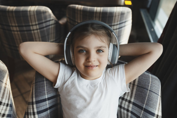 快乐的女婴，5岁，戴着耳机坐在椅子上听音乐图片下载