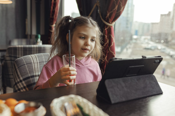 一个5岁的小女孩，手里拿着一杯果汁，坐在咖啡馆里图片下载