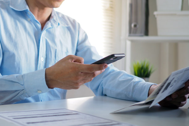 商人在网上收到单据发票后，用手机扫描条形码或二维码支付信用卡账单。支付，接收，支付电费，无钱的数字支付，技术图片下载