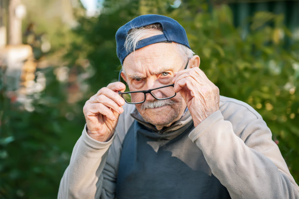 一位戴着棒球帽的88岁老人戴上了眼镜。一个戴眼镜的老农民在花园里的画像图片下载