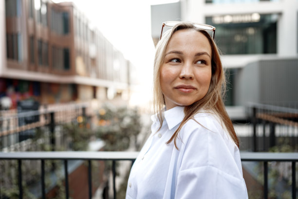 年轻的办公室女性站在阳台上欣赏城市景观的肖像图片下载