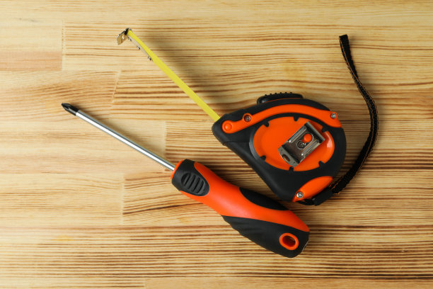 螺丝刀和卷尺在木制背景上，靠近图片下载