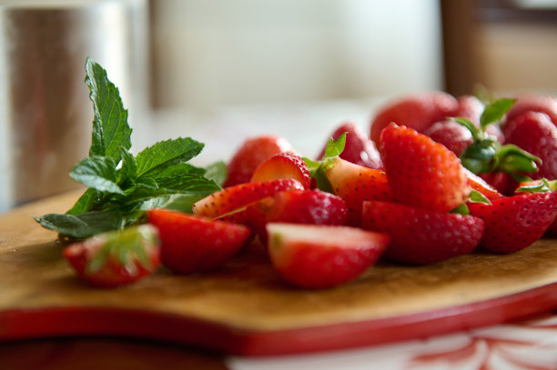 食物背景与切片成熟的有机新鲜草莓和薄荷叶在一个木制砧板。健康营养图片下载
