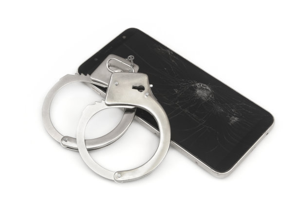 手铐和智能手机，破碎的屏幕被隔离在白色背景上。图片下载