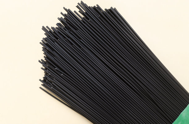 一堆生的黑色意大利面，在黄色背景上涂上墨鱼墨水。意大利菜的概念。水平方向。有选择性的重点。前视图。图片下载