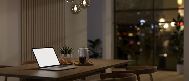 在一个现代舒适的餐厅里，一个白色屏幕的笔记本电脑模型在木制餐桌上图片下载