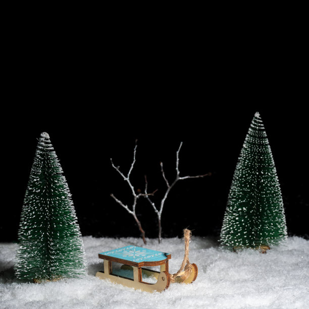 玩具小雪橇在白雪覆盖的森林里，在圣诞树之间的夜晚。冬季运动。创意冬日贺卡。图片下载