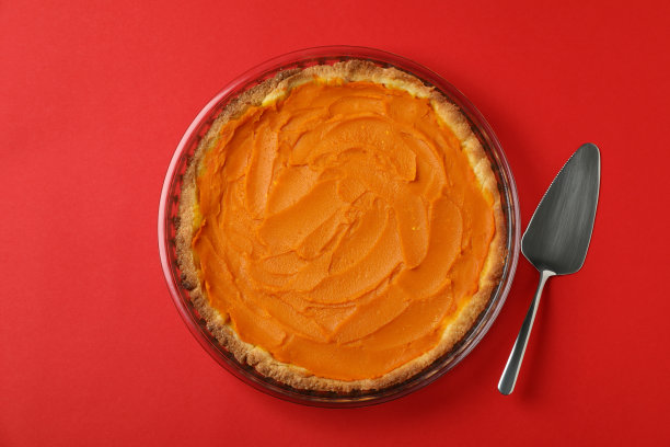 南瓜派和蛋糕铲在红色的背景图片下载