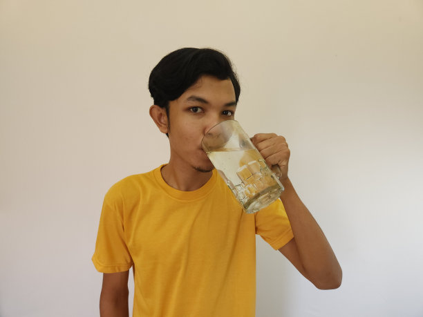 一名亚洲男子正在饮用白色背景的水图片下载