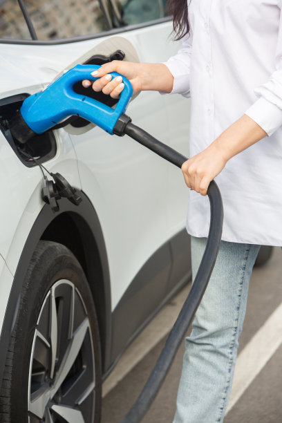 年轻的女商人在电动汽车充电站给她的电动汽车加油图片下载