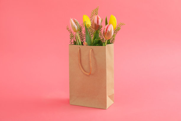 纸袋与花在粉红色的背景图片下载