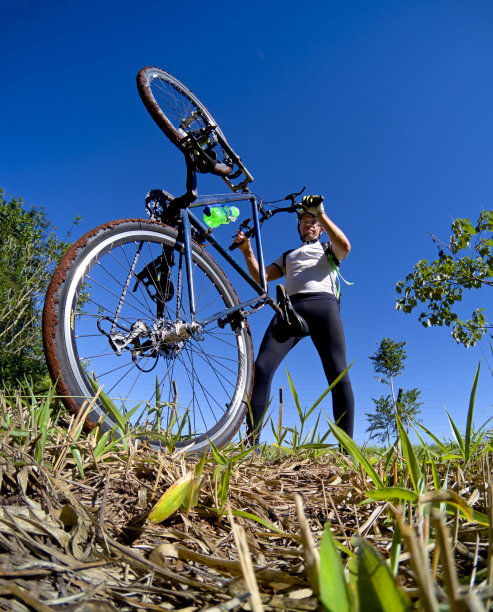 在绿色植被和土地的自然环境中，女运动员骑着一辆车轮泥泞的自行车图片下载
