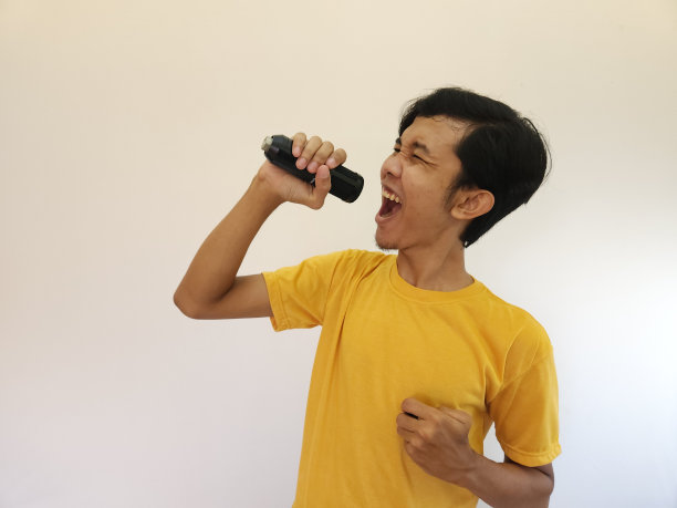 一个亚洲人拿着麦克风唱歌。开心放松，享受卡拉ok图片下载