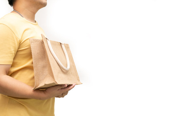 男子手持黄麻袋或麻袋在白底。可重复使用的购物袋。图片下载