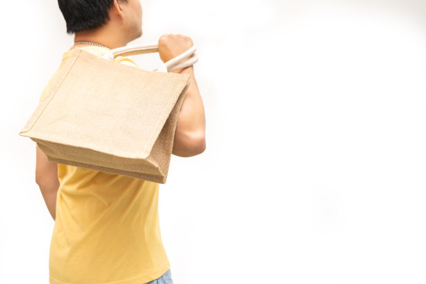 男子手持黄麻袋或麻袋在白底。可重复使用的购物袋。图片下载