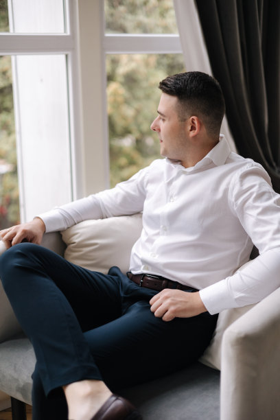 一个人坐在家里的大窗户前。新郎的早晨。结婚的那一天图片下载