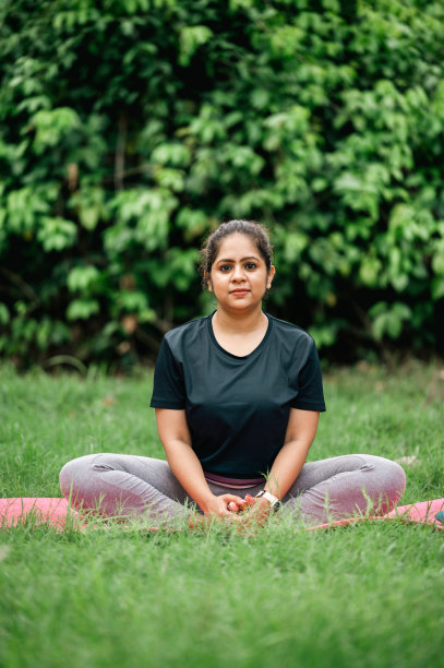 在公园里，一名女子以蝴蝶姿势坐着，光着脚伸展双腿图片下载
