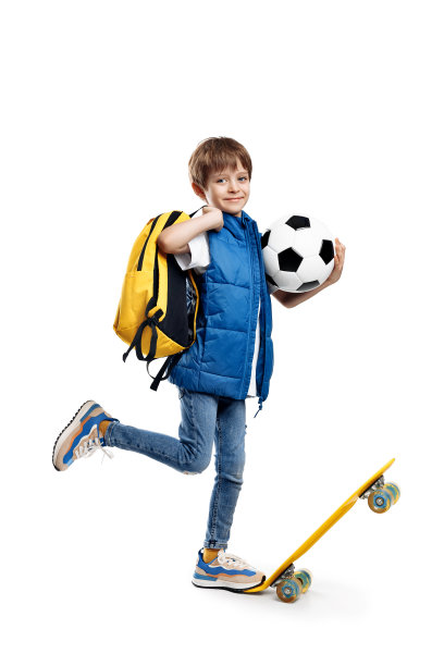 精力充沛的小男孩带着滑板和背包，拿着白色背景的足球。回到学校。图片下载