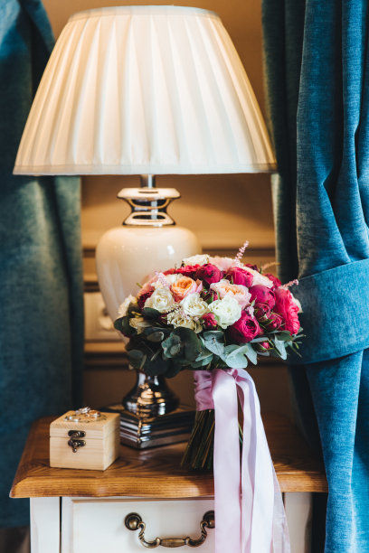 新娘卧室里靠近台灯的木桌上，美丽的婚礼花束的垂直照片。婚姻的准备。结婚的概念。图片下载