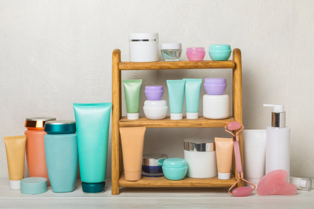盥洗室里靠白墙的架子上放着护理化妆品。洗洁精，爽肤水，精华液和身体乳，瓜沙按摩辊，洗发水和护发膏。装饰和护理化妆品。美丽的概念。图片下载